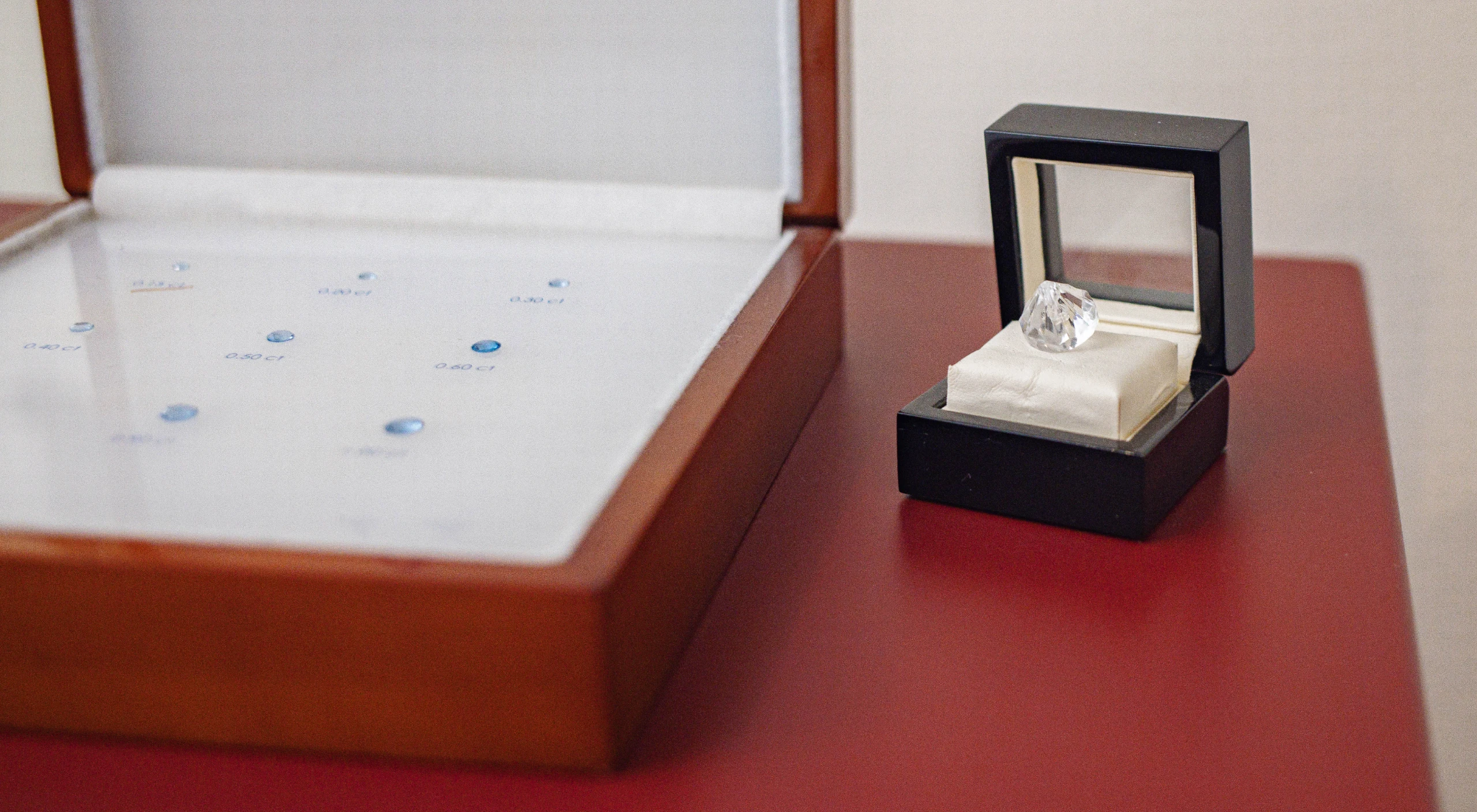 Glasschale mit Sand, Kerze und Steinherz auf Tisch, Kerzenständer in Engelform, Korb mit Teelichtern und Zettel mit Stift.